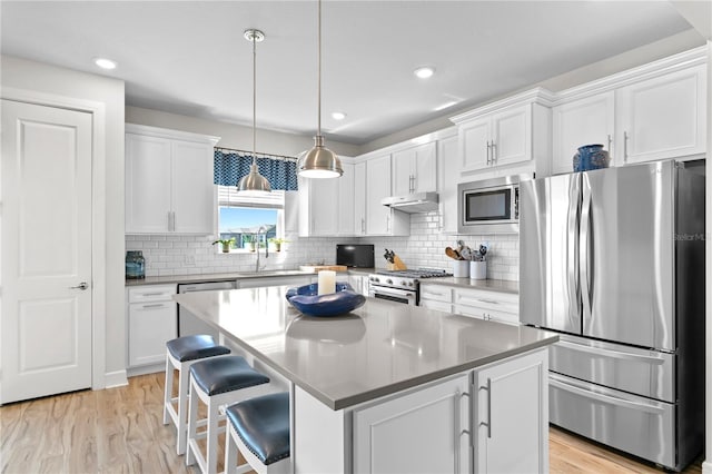 kitchen with white cabinetry, backsplash, decorative light fixtures, a kitchen island, and appliances with stainless steel finishes