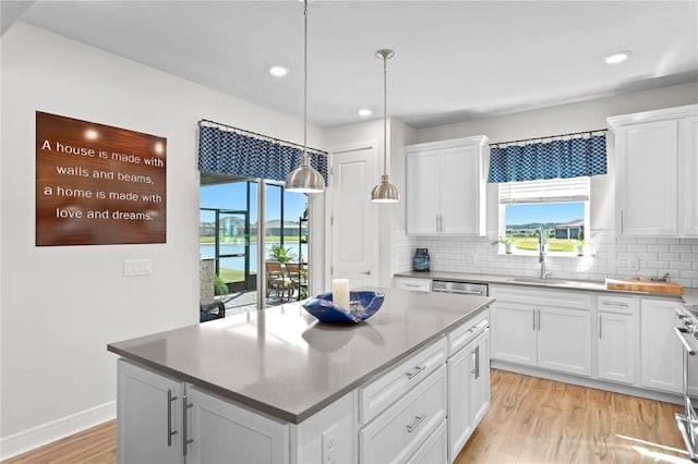 kitchen with tasteful backsplash, pendant lighting, range, a center island, and white cabinetry