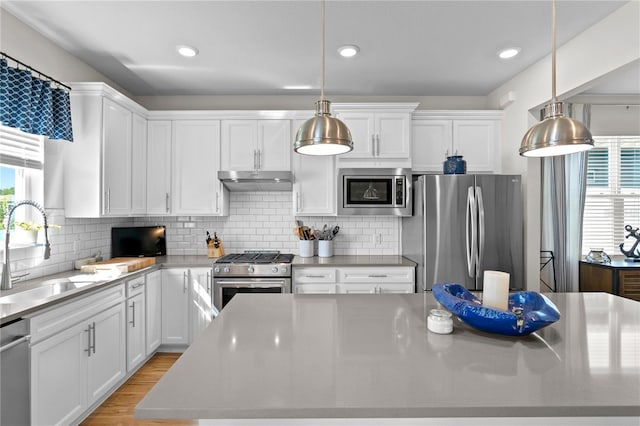 kitchen with white cabinetry, sink, hanging light fixtures, tasteful backsplash, and appliances with stainless steel finishes