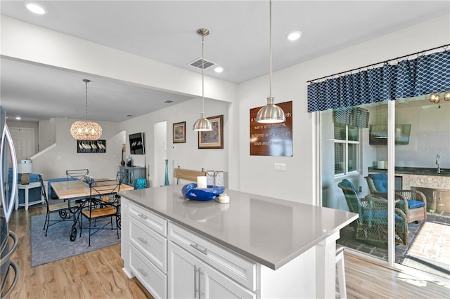 kitchen with a center island, white cabinetry, hanging light fixtures, and an inviting chandelier