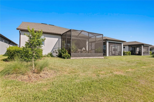 rear view of house featuring a yard and glass enclosure