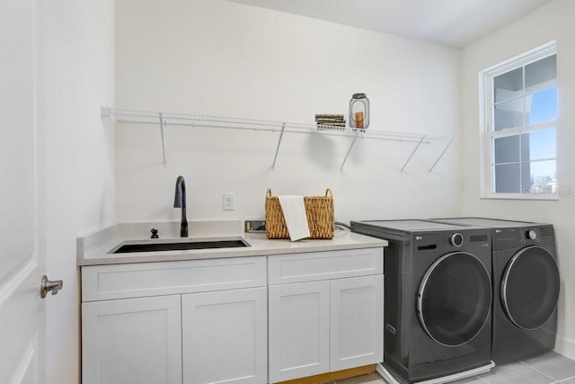 clothes washing area with washer and clothes dryer, sink, and cabinets