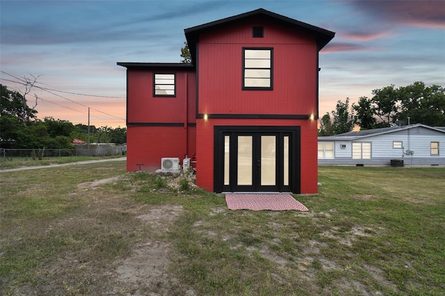 back house at dusk with a yard and french doors