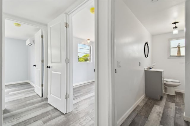 bathroom featuring an AC wall unit, plenty of natural light, vanity, and wood-type flooring