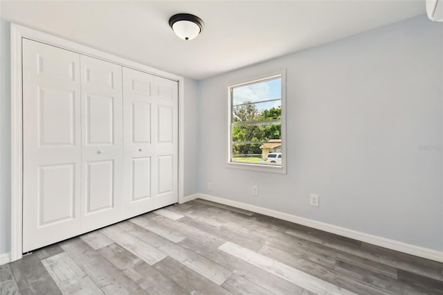 unfurnished bedroom with light hardwood / wood-style flooring and a closet