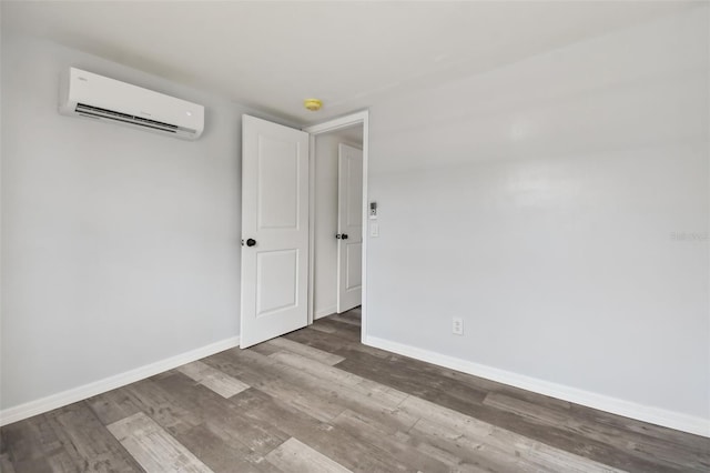 unfurnished room with a wall mounted air conditioner and wood-type flooring