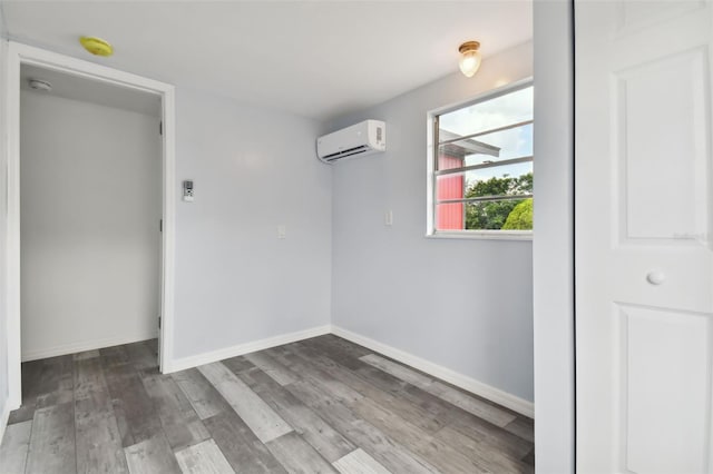 unfurnished room with a wall mounted air conditioner and hardwood / wood-style flooring