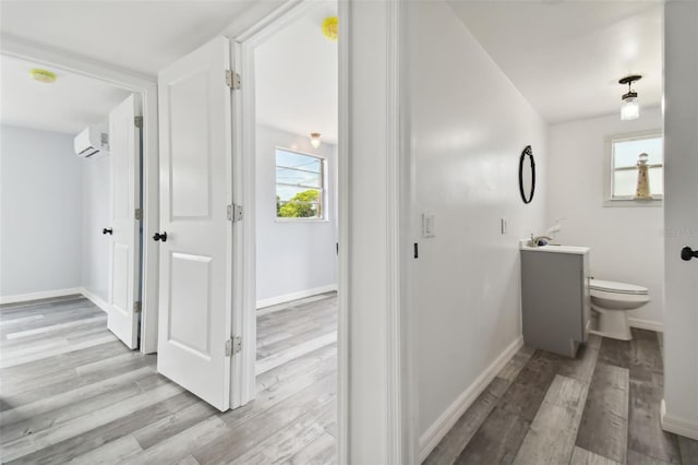 bathroom with a wall mounted air conditioner, hardwood / wood-style floors, vanity, and toilet