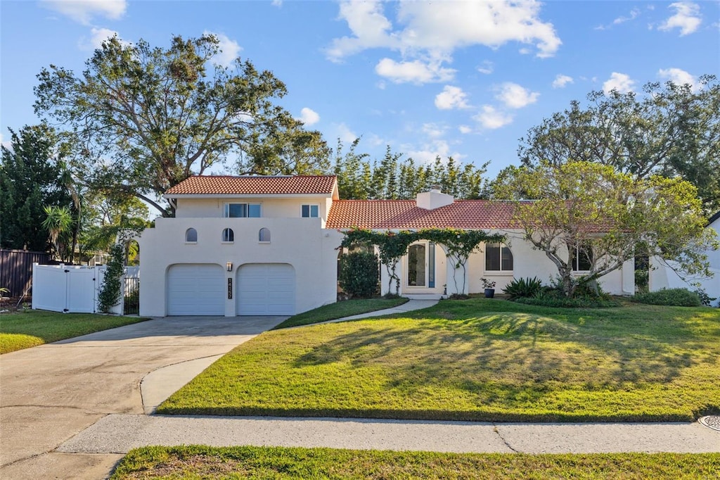 mediterranean / spanish-style home featuring a garage and a front yard