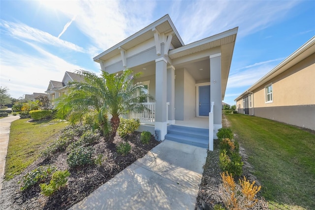 view of exterior entry featuring covered porch and a yard