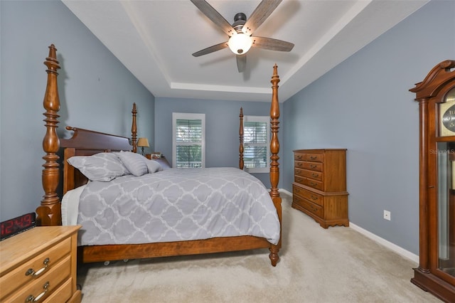 carpeted bedroom with a raised ceiling and ceiling fan