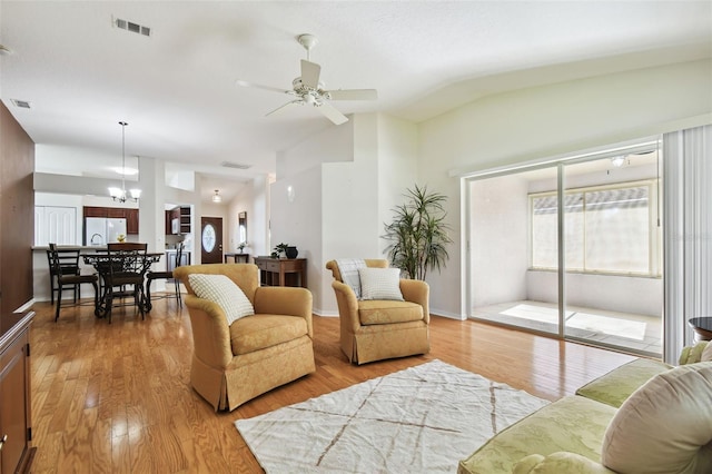 living room with vaulted ceiling, ceiling fan with notable chandelier, and wood-type flooring