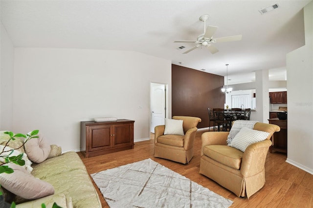 living room featuring light wood-type flooring, lofted ceiling, and ceiling fan with notable chandelier