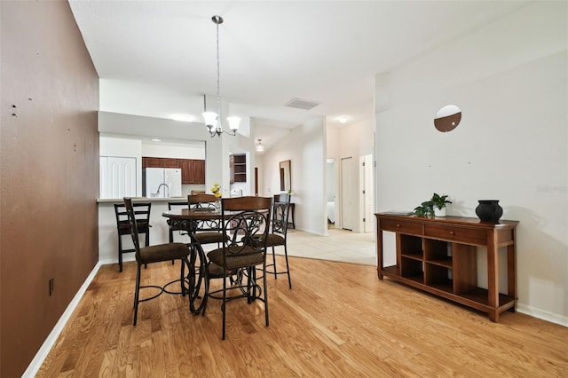 dining space with light wood-type flooring and a notable chandelier