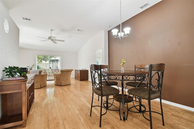 dining room featuring light hardwood / wood-style floors, vaulted ceiling, and ceiling fan with notable chandelier