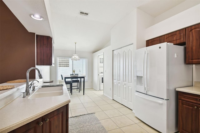 kitchen with lofted ceiling, sink, hanging light fixtures, light tile patterned floors, and white fridge with ice dispenser