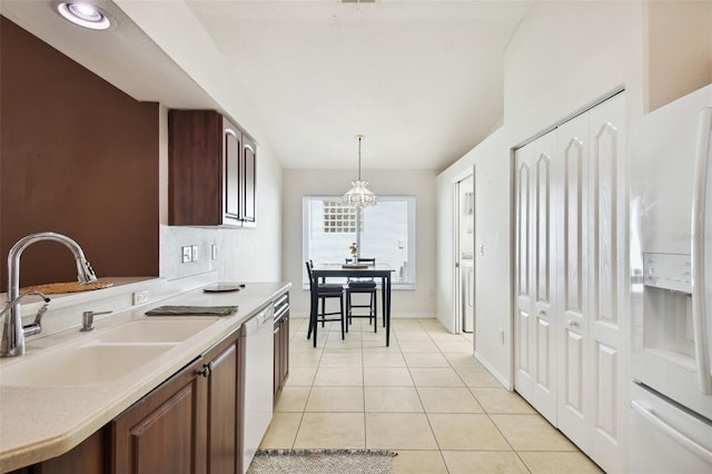 kitchen featuring decorative light fixtures, a notable chandelier, sink, white appliances, and light tile patterned floors