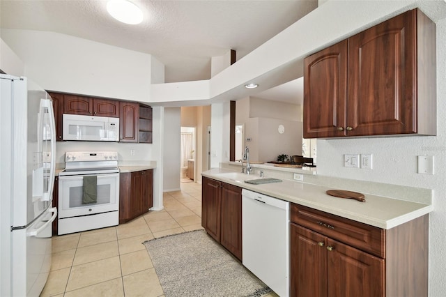 kitchen with light tile patterned floors, a high ceiling, white appliances, a textured ceiling, and sink