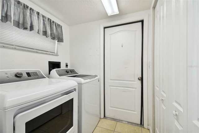 washroom with light tile patterned floors, independent washer and dryer, and a textured ceiling