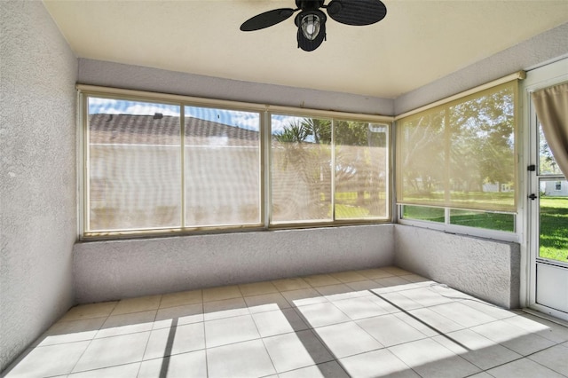 unfurnished sunroom featuring ceiling fan and plenty of natural light