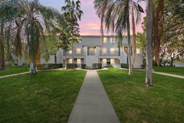 view of front of home with a lawn and a balcony