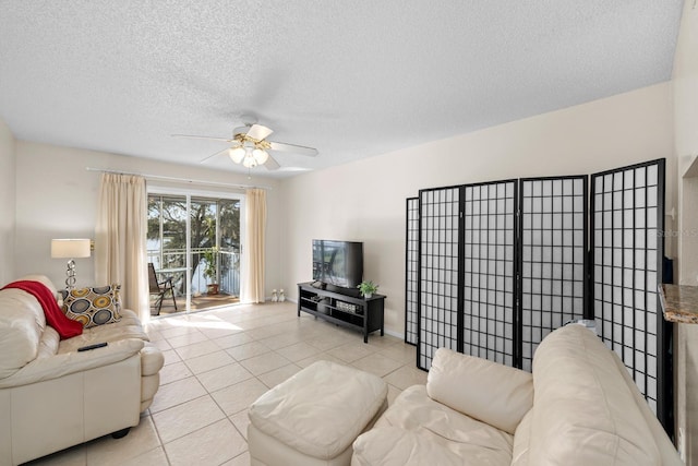 living room with ceiling fan, light tile patterned floors, and a textured ceiling