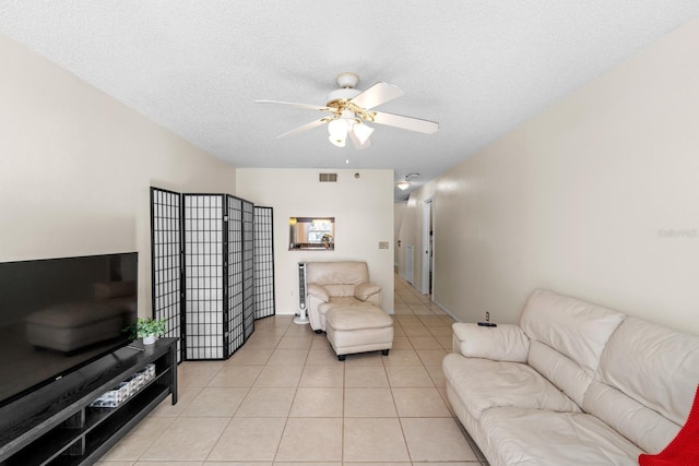 living room with ceiling fan, light tile patterned floors, and a textured ceiling