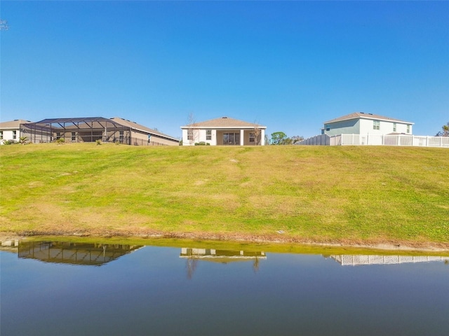 rear view of house featuring a water view and a lawn