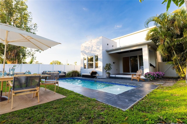 rear view of property with a yard, an outdoor hangout area, a fenced in pool, and a patio