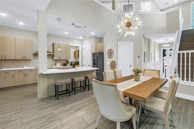 2246 Fiesta Dr, Sarasota, FL 34231 - dining room with a high ceiling, a chandelier, stairway, wood finish floors, and recessed lighting