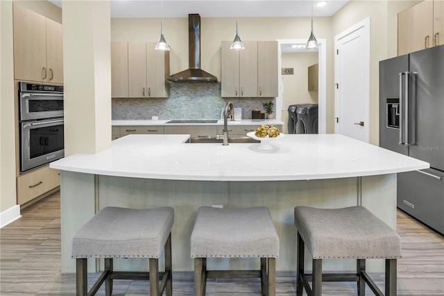 2246 Fiesta Dr, Sarasota, FL 34231 - kitchen with wall chimney exhaust hood, stainless steel appliances, washer and clothes dryer, and a kitchen bar