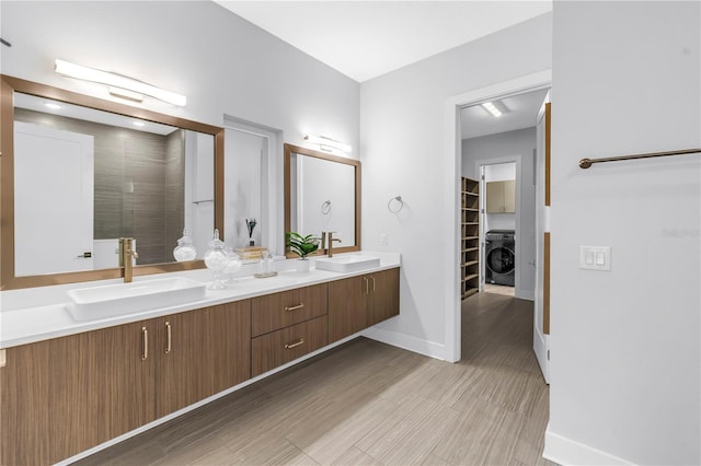 2246 Fiesta Dr, Sarasota, FL 34231 - bathroom featuring washer / dryer, double vanity, a walk in closet, a shower, and wood finished floors