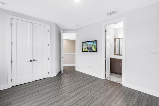 2246 Fiesta Dr, Sarasota, FL 34231 - unfurnished bedroom featuring a closet, ensuite bath, and wood finished floors