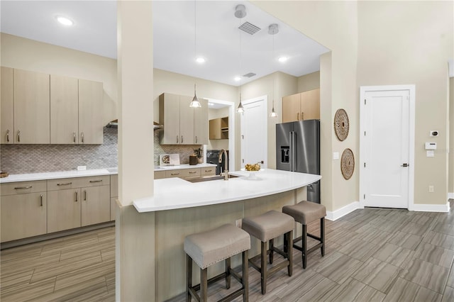 2246 Fiesta Dr, Sarasota, FL 34231 - kitchen featuring high quality fridge, backsplash, a breakfast bar, light countertops, and wood tiled floors