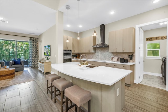 2246 Fiesta Dr, Sarasota, FL 34231 - kitchen featuring wall chimney range hood, light countertops, a breakfast bar area, backsplash, and cooktop