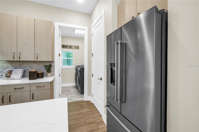 2246 Fiesta Dr, Sarasota, FL 34231 - kitchen with high end fridge, washer and dryer, tasteful backsplash, light stone countertops, and light brown cabinets