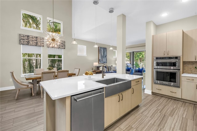 2246 Fiesta Dr, Sarasota, FL 34231 - kitchen with stainless steel appliances, light countertops, light brown cabinets, an island with sink, and decorative light fixtures