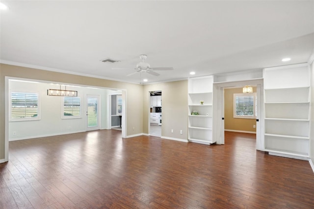 unfurnished living room featuring ceiling fan with notable chandelier, a healthy amount of sunlight, ornamental molding, and dark hardwood / wood-style floors