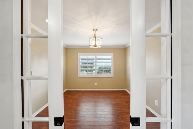 unfurnished room with crown molding, hardwood / wood-style floors, and a notable chandelier