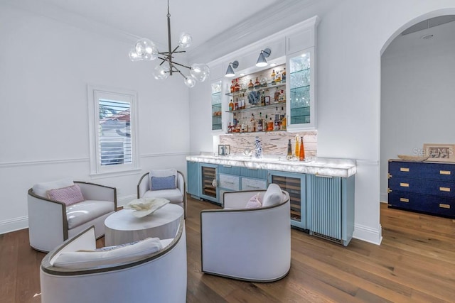 bar featuring dark hardwood / wood-style floors, blue cabinets, crown molding, a chandelier, and pendant lighting