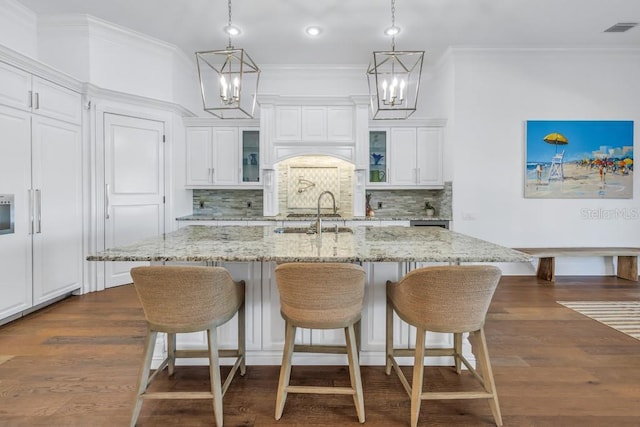 kitchen featuring backsplash, an island with sink, white cabinetry, and sink