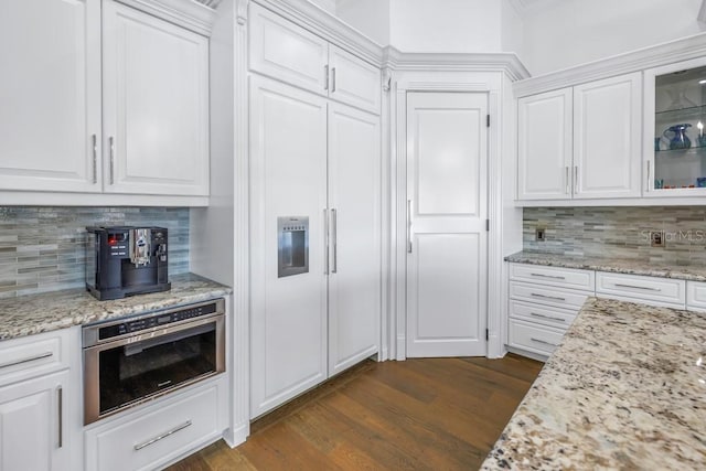 kitchen featuring white cabinets, stainless steel oven, and backsplash