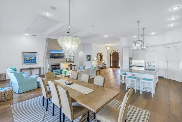 dining area featuring crown molding, a large fireplace, dark hardwood / wood-style flooring, and sink