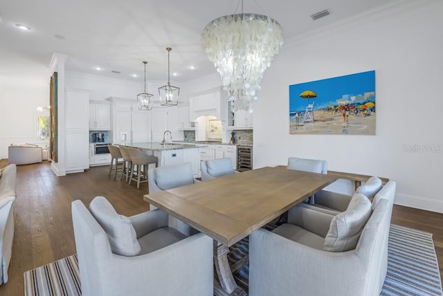 dining area with ornamental molding, beverage cooler, sink, a chandelier, and dark hardwood / wood-style floors