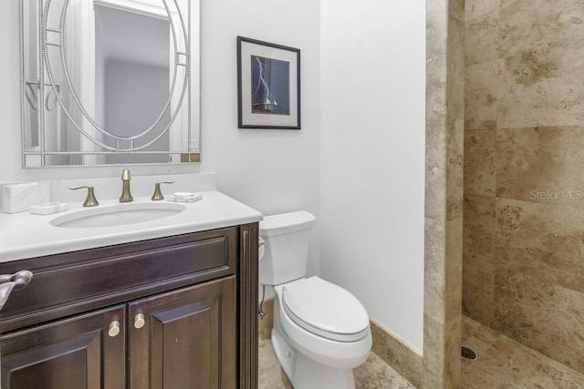 bathroom featuring vanity, toilet, and a tile shower