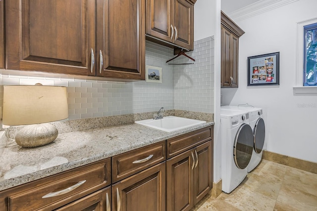 clothes washing area with separate washer and dryer, crown molding, sink, and cabinets