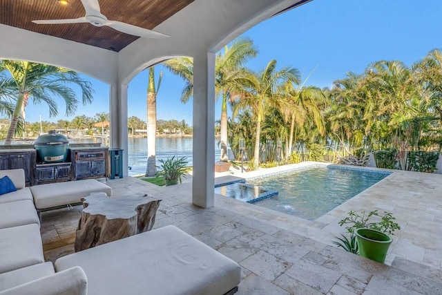 view of swimming pool featuring an outdoor kitchen, area for grilling, ceiling fan, a water view, and a patio