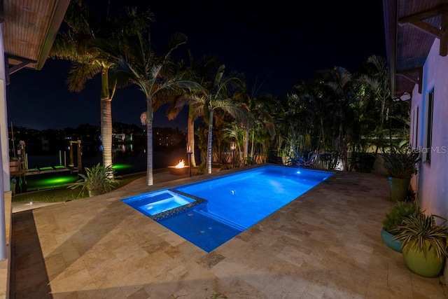 pool at twilight featuring a patio area and an in ground hot tub