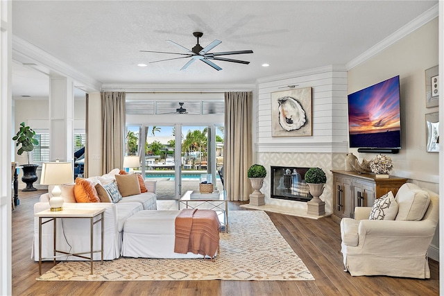 living room with a tile fireplace, a wealth of natural light, hardwood / wood-style flooring, and ornamental molding