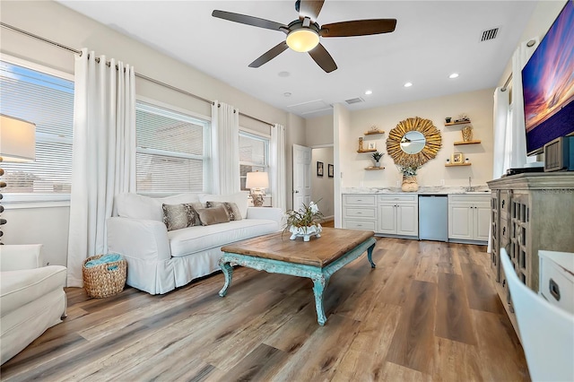 living room featuring light wood-type flooring, plenty of natural light, ceiling fan, and sink